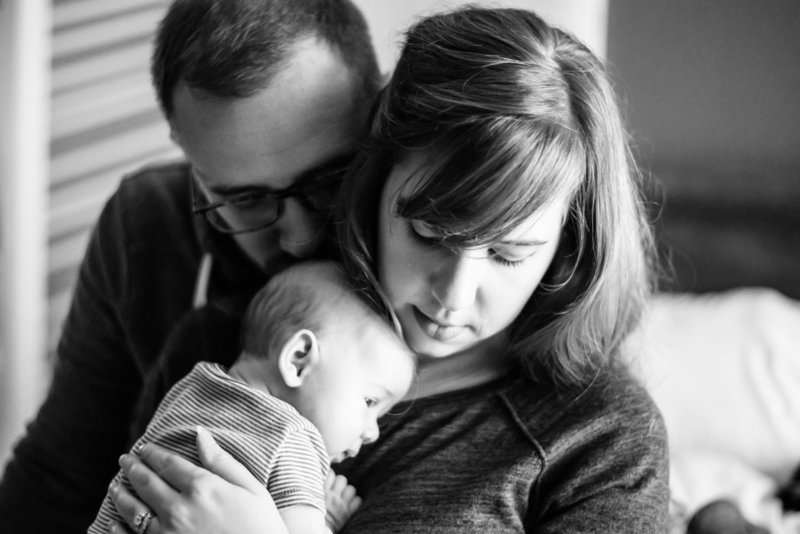Parents snuggle newborn at home