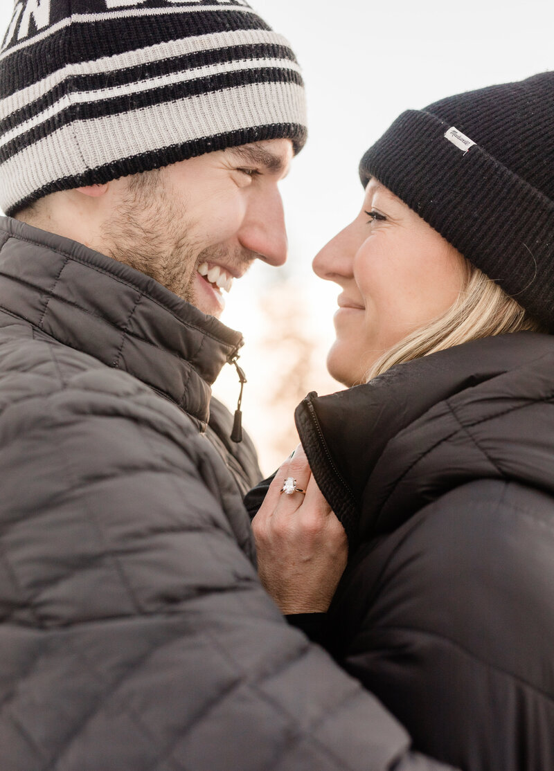 A close up of a couple in black jackets snuggling close on a cold day