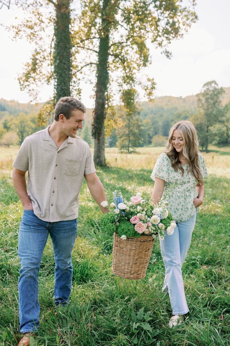 Savanna and her husband, founders of Oopsie Daisy Florals walking through local NC greenery with a custom floral design basket for a luxury wedding.