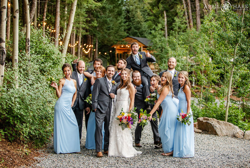 Wedding party candid group photo with covered bridge backdrop at Idaho Springs Blackstone Rivers Ranch Wedding Venue