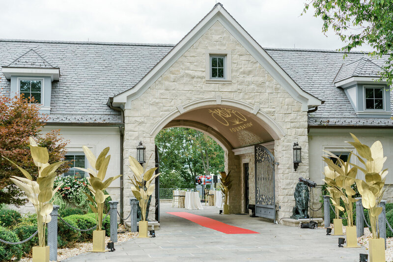 Stone building entrance with a red carpet and gold decorations.