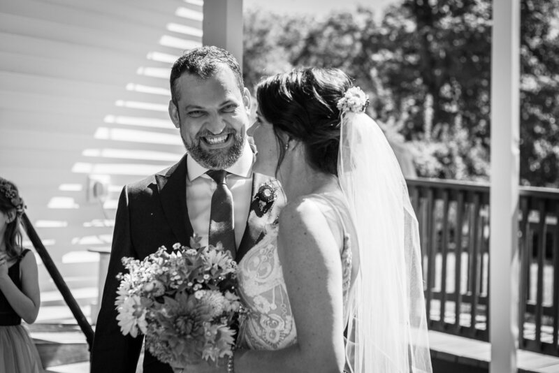 groom smiling at bride holding flowers