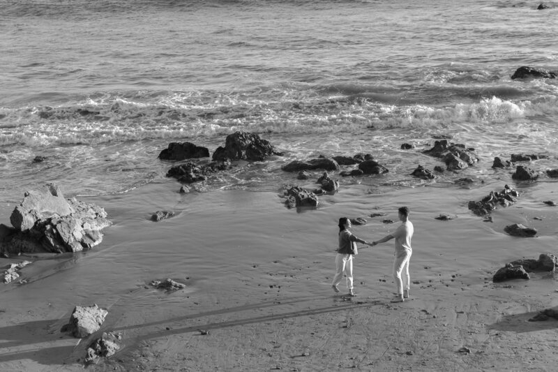 A couple holding hands and walking along the water's edge