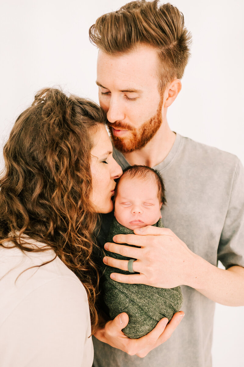 Springfield Mo newborn photographer The XO Photography captures mom and dady holding swaddled newborn baby boy