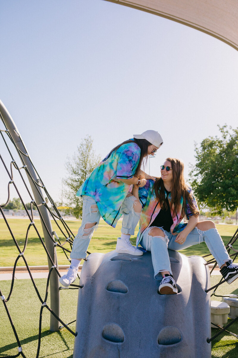 Two friends laughing while on top of playground equipment.