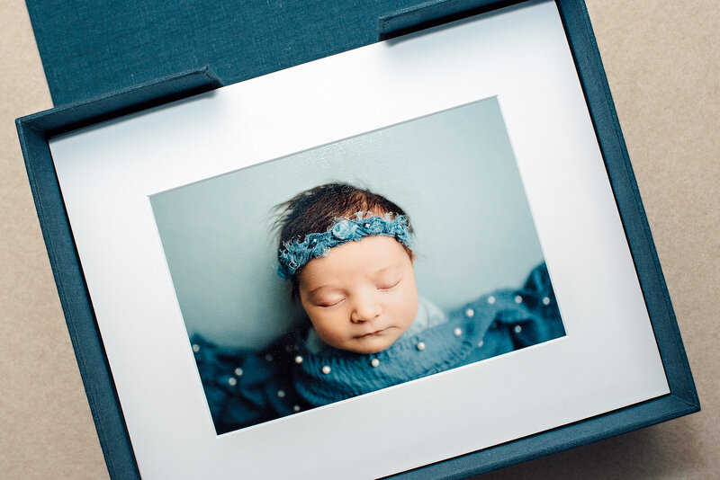 Matted newborn portraits in blue linen folio box in Jacksonville, FL.