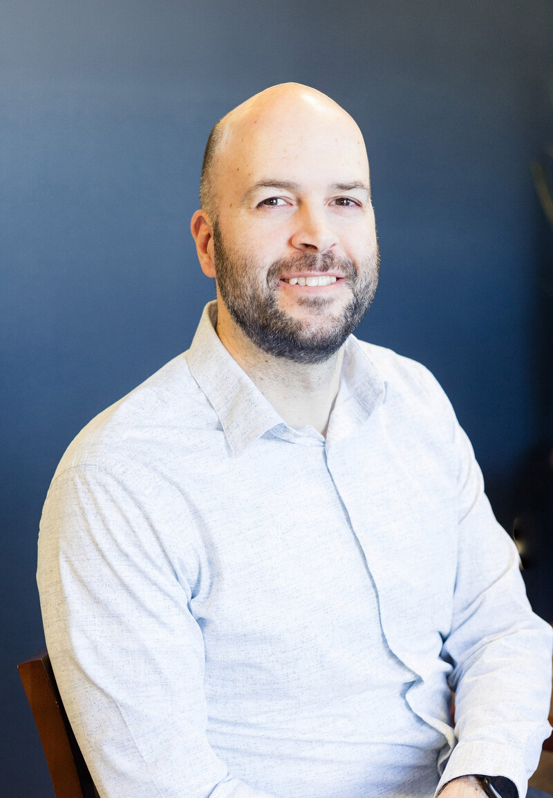 Aaron sitting in front of a blue wall at Thompson CPA LLC