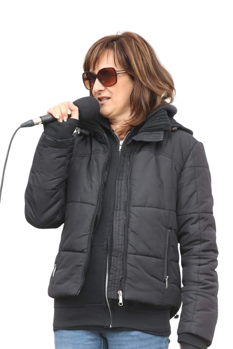 Bea Weir, founder of EnerBea, speaking while holding a microphone during a presentation on wholistic health and vibrational remedies.