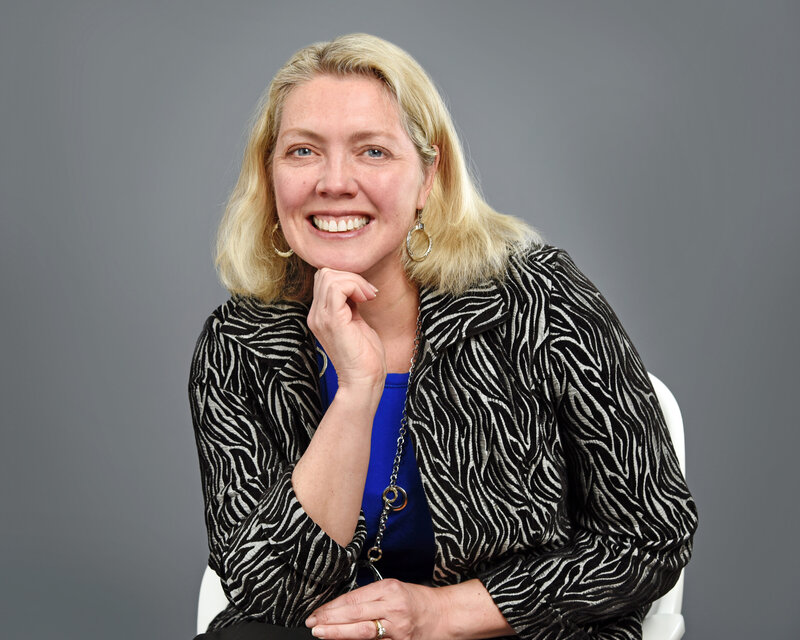 Portrait of illustrator and graphic designer Ellen Morse in studio with blue blouse and black and silver jacket.  Photo by TBC Photo Buffalo NY