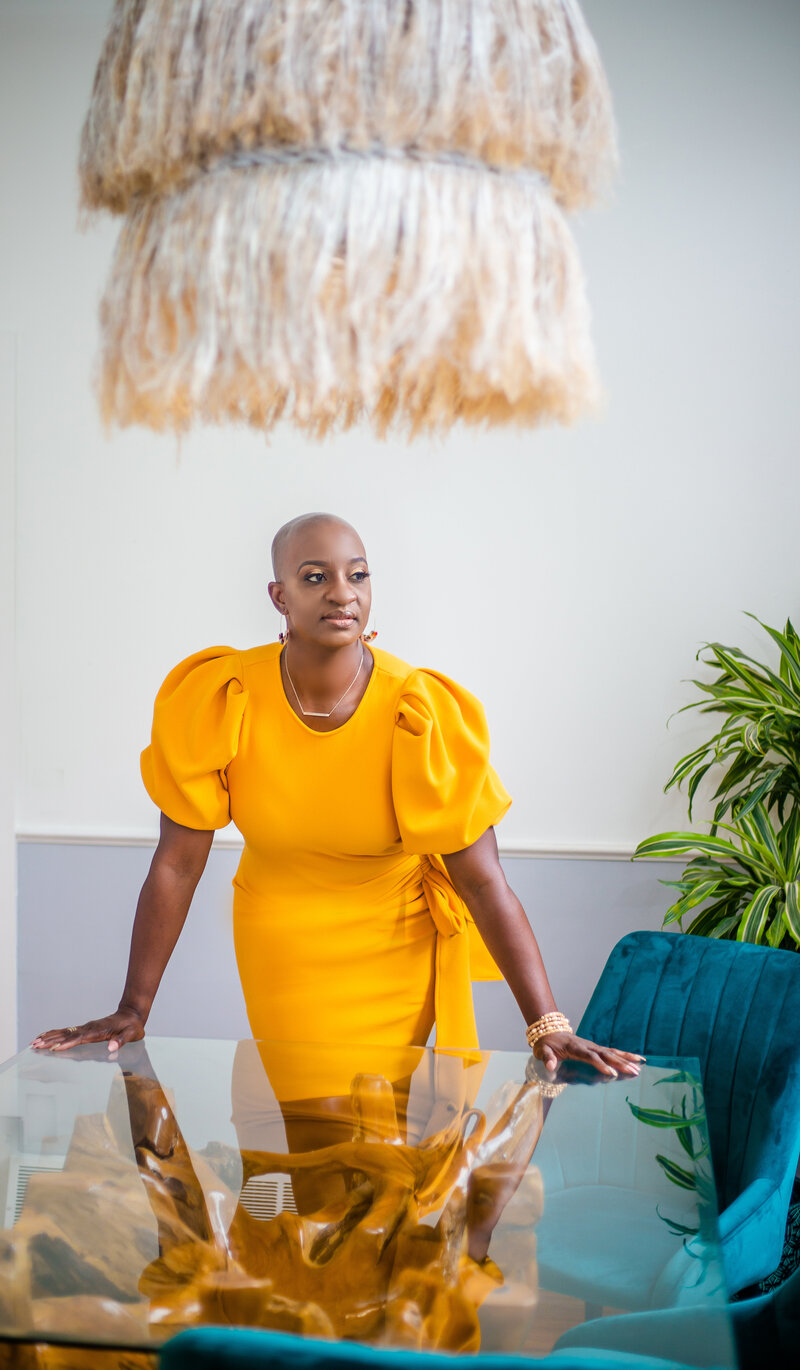 Bald black woman realtor wearing yellow dress