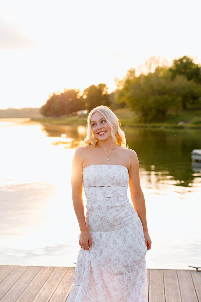 girl poses in field for senior photos in kansas city missouri