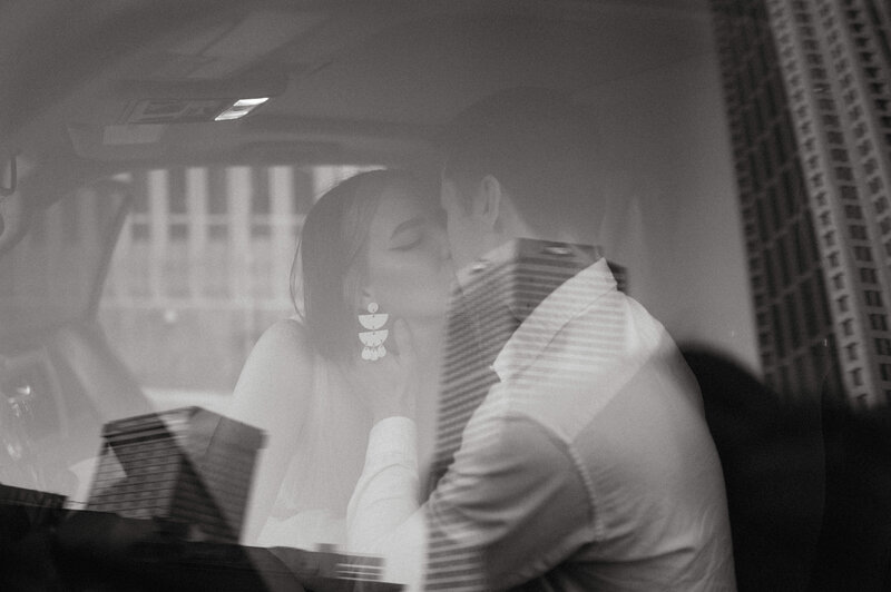 An elopement couple kisses in their car on a rooftop in Atlanta.