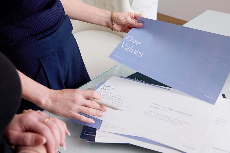 Hands holding a “Core Values” brand workbook during a strategy session at Jennifer Taormina & Co.—part of the custom branding process.