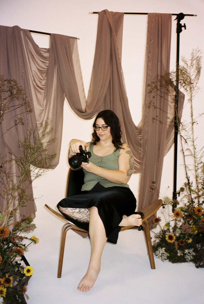 Colleen sits in a chair while looking into a camera.