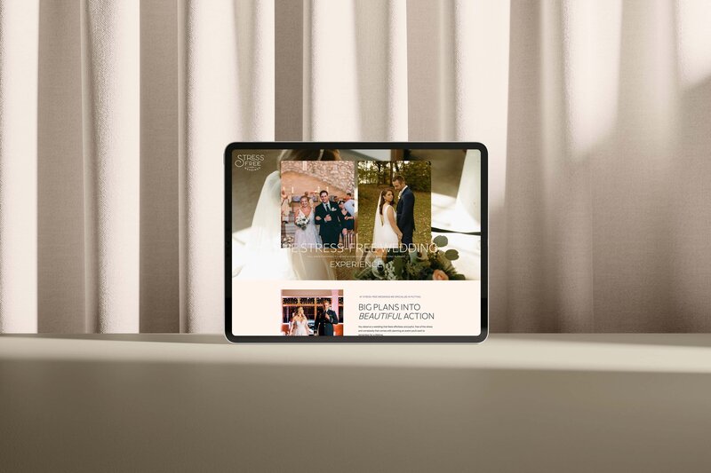 A tablet displaying a Showit web design for wedding planners rests on a surface in front of beige curtains. The website shows a couple at their wedding and text promoting stress-free wedding planning.