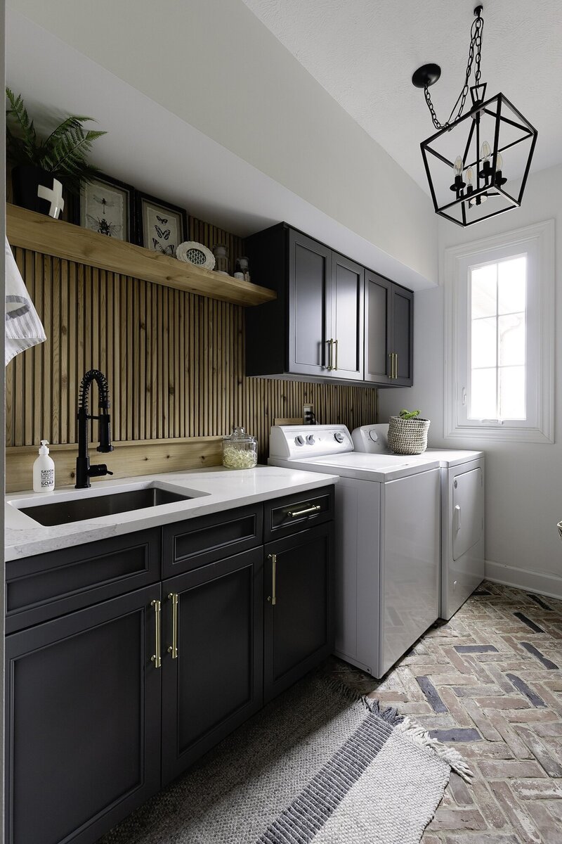 Modern laundry room with black cabinets contrasting a wooden backsplash