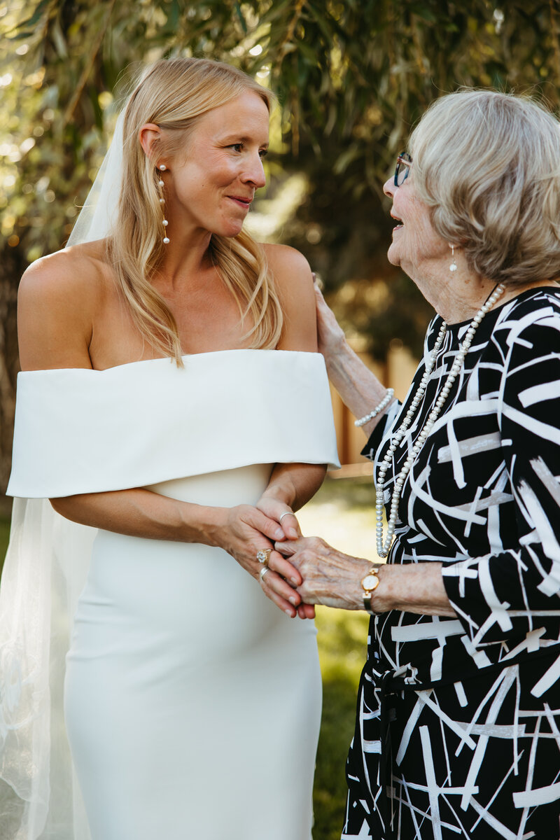 bride holds her grandmas hand on her wedding day