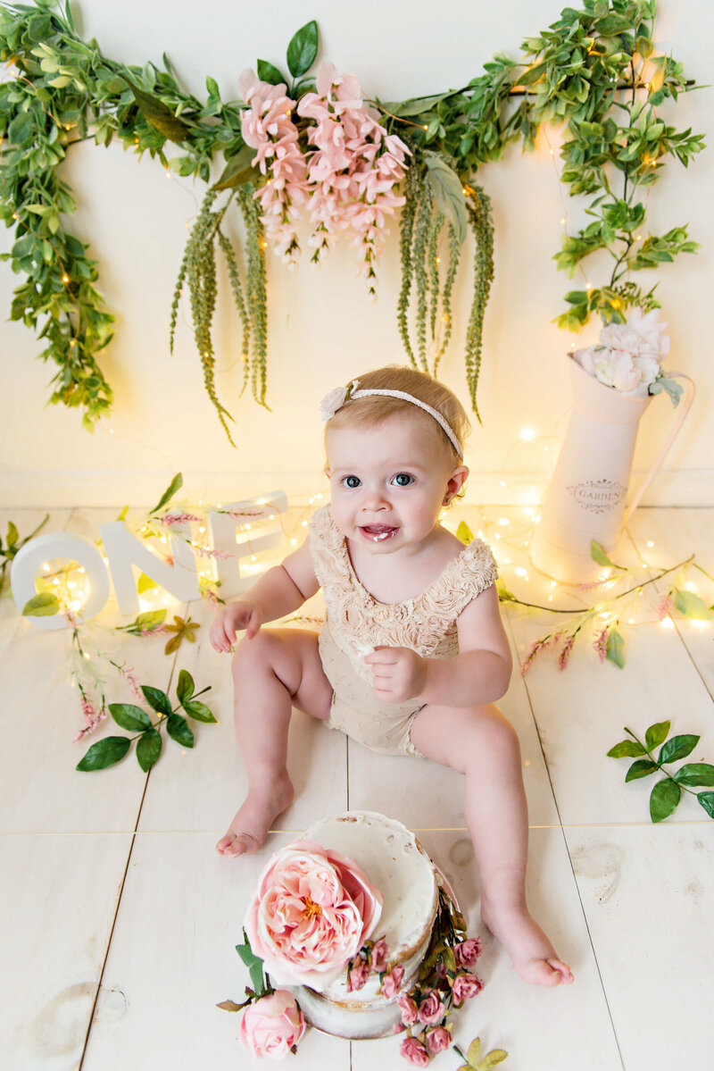First birthday cake smash photography session in Burlington, Ontario wearing a vintage onesie with florals.