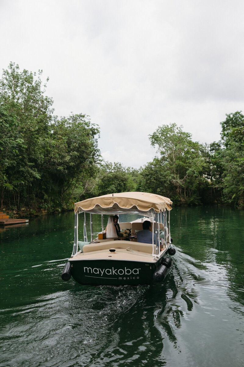 Bride and Groom floating away on a boat at the Rosewood Mayakoba luxury resort in Tulum Mexico, documented by Andrea-Marie Photography