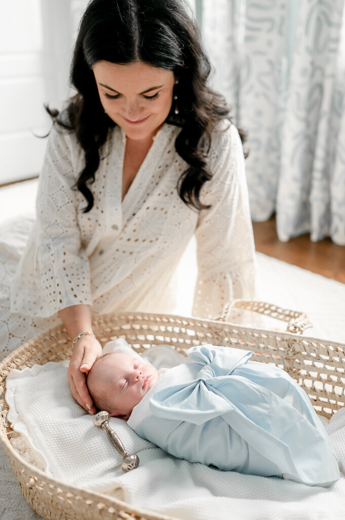 Newborn baby lays in blue bow swaddle sleeping in a Moses basket