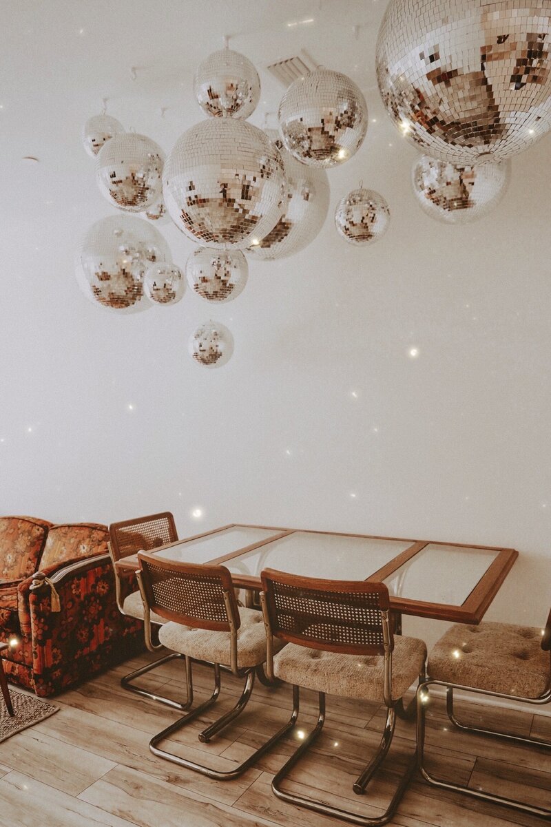 retro dining table and chairs with disco balls hanging above it