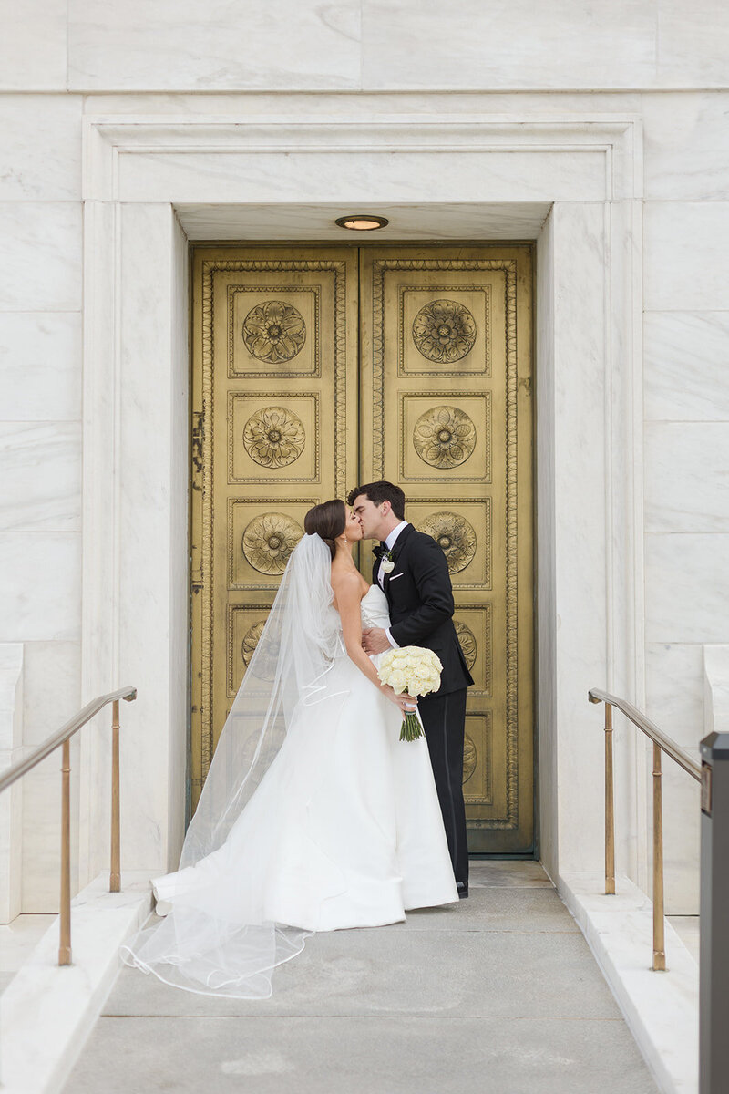 bride and groom kiss in front of a church in washington dc