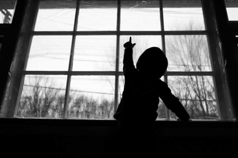 A silhouette of a child standing in front of a window.
