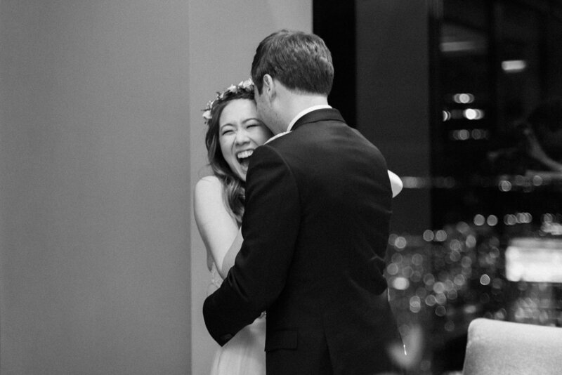 a groom hugging his wife, who is laughing, at canoe restaurant in Toronto. 