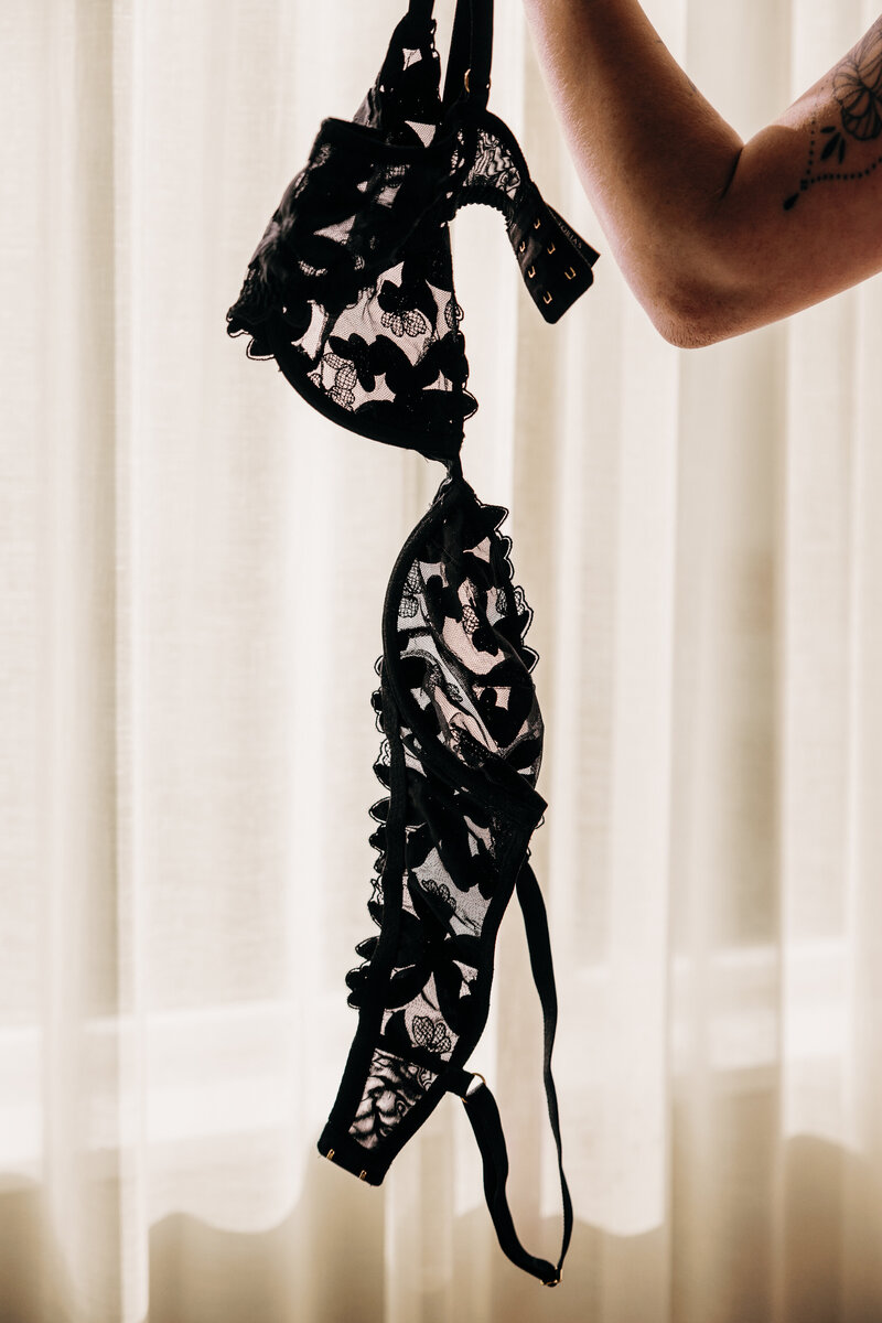 Boudoir photo woman's arm holding black lace bra