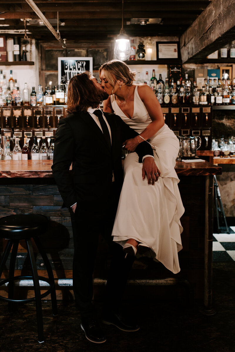 A groom kissing his bride's cheek while she closes her eyes and holds her bouquet.