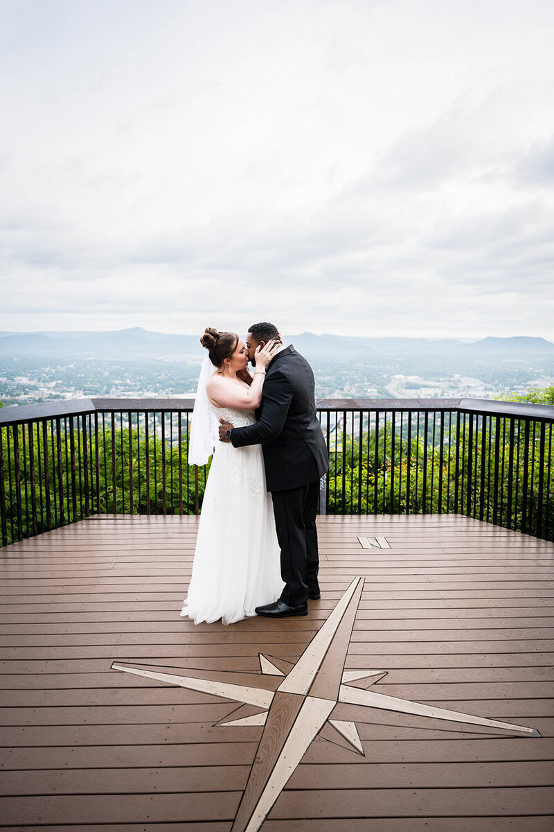 A couple shares their first kiss at Mill Mountain with the Blue Ridge Mountains as their backdrop for their Roanoke, Virginia elopement wedding day.
