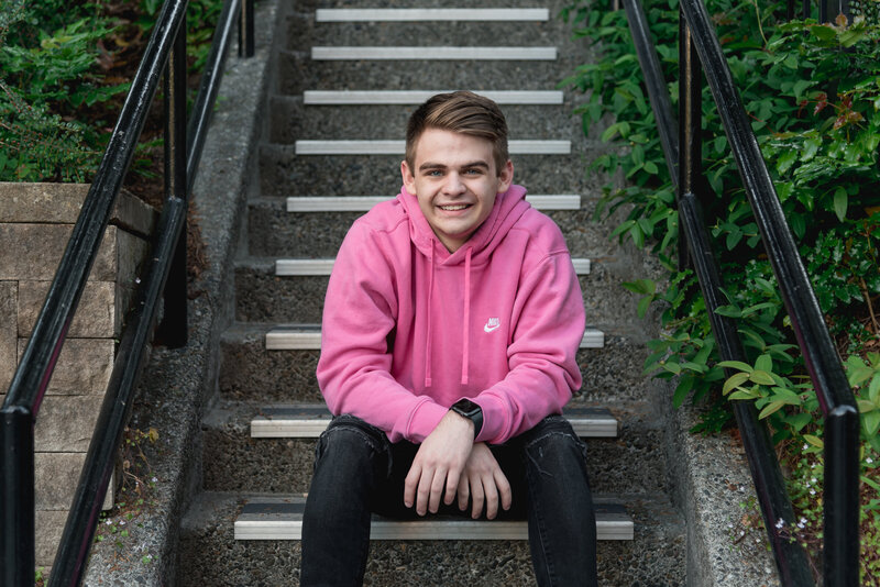 High School Senior sitting on stairs relaxed in pink nike hoodie
