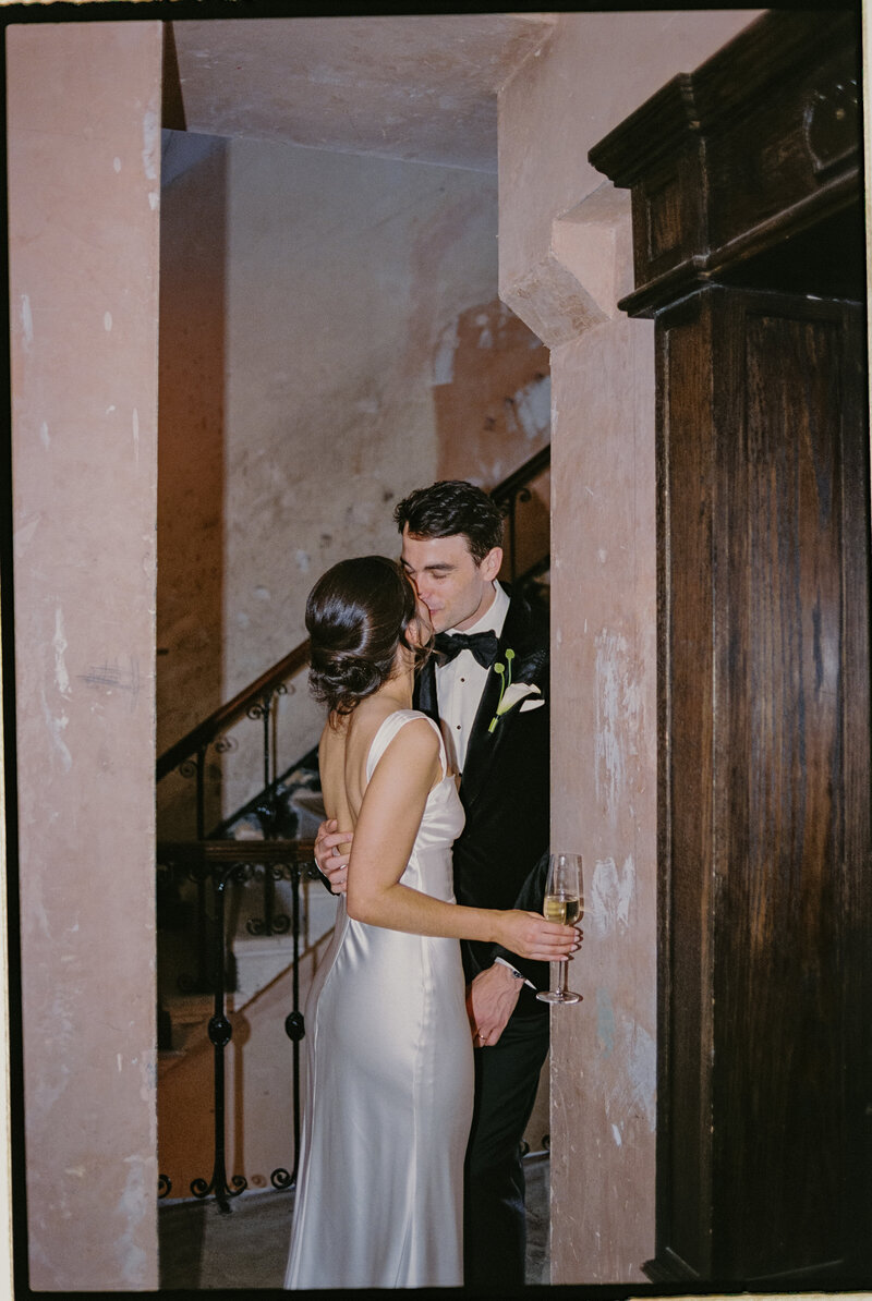 Couple sharing quiet moment before reception begins, captured candidly on stairs.