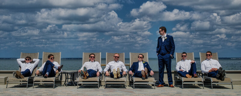 Groomsmen in suits sitting on deck chairs at the New Jersey shore on a sunny May day, winner of the PPA IPC Imaging Excellence Award.