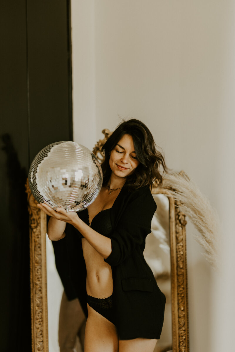 Femme allongée sur le dos en lingerie noire, souriante, capturée par Laura, photographe portrait en Vendée