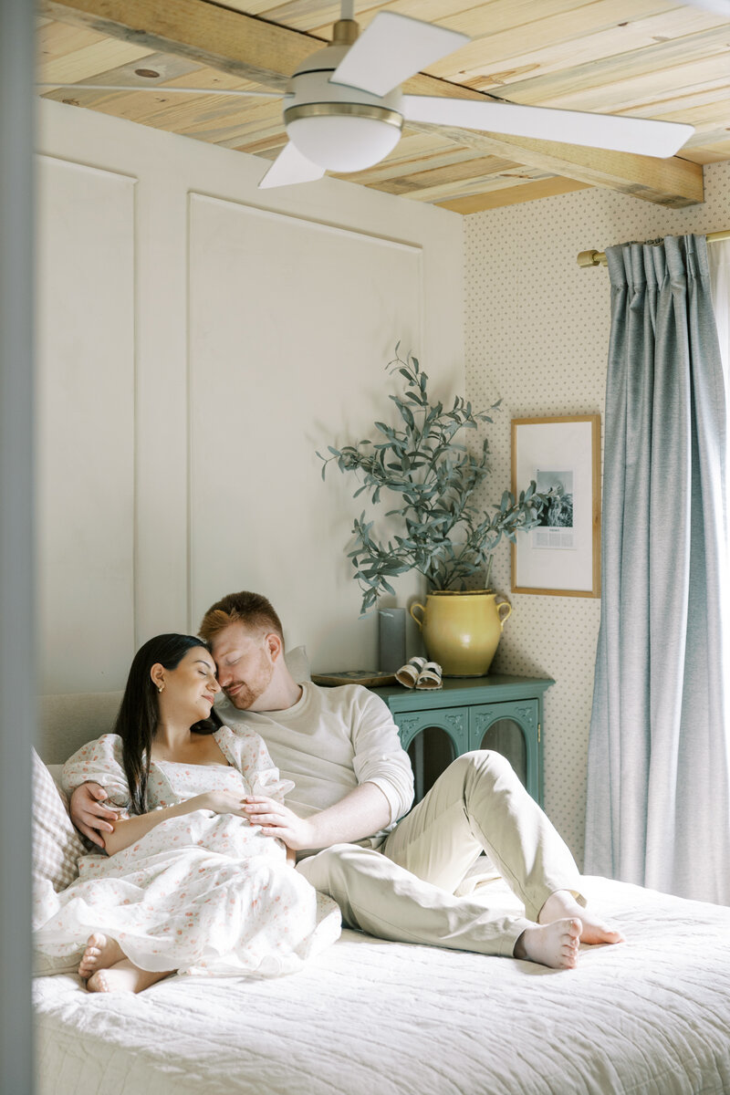 Couple holding mom's pregnant belly during a cozy, light-filled maternity shoot
