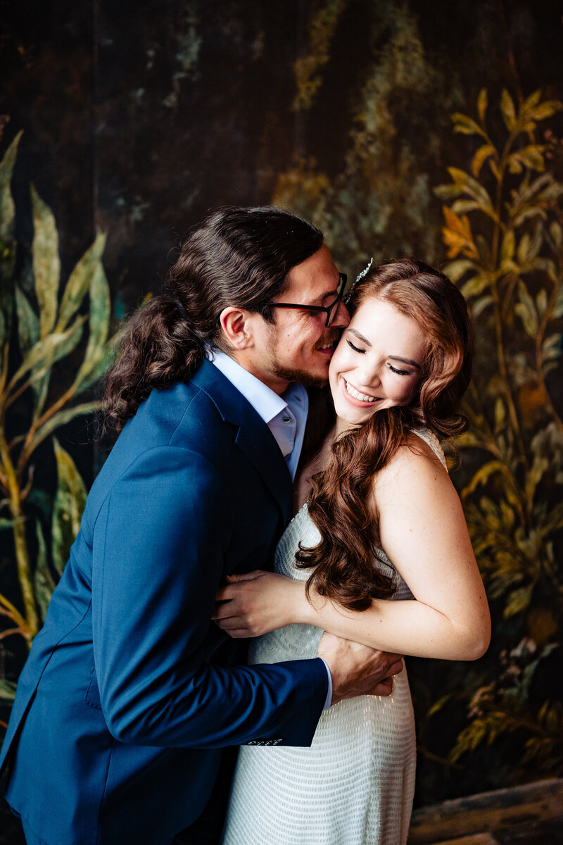 A wedding couple cuddling after the ceremony in front of a floral wall at the Mez in Toledo Ohio