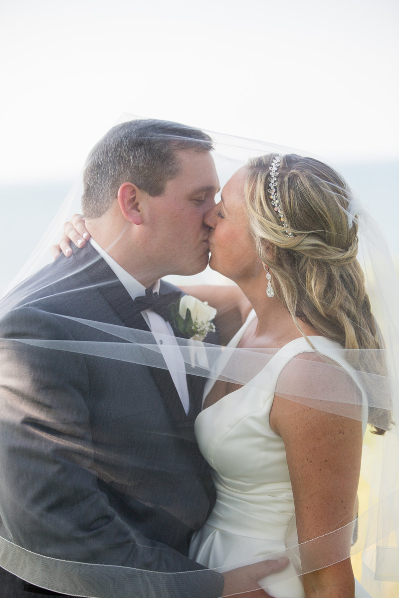Bride and groom kiss under bride's veil at Lawrence Park golf club