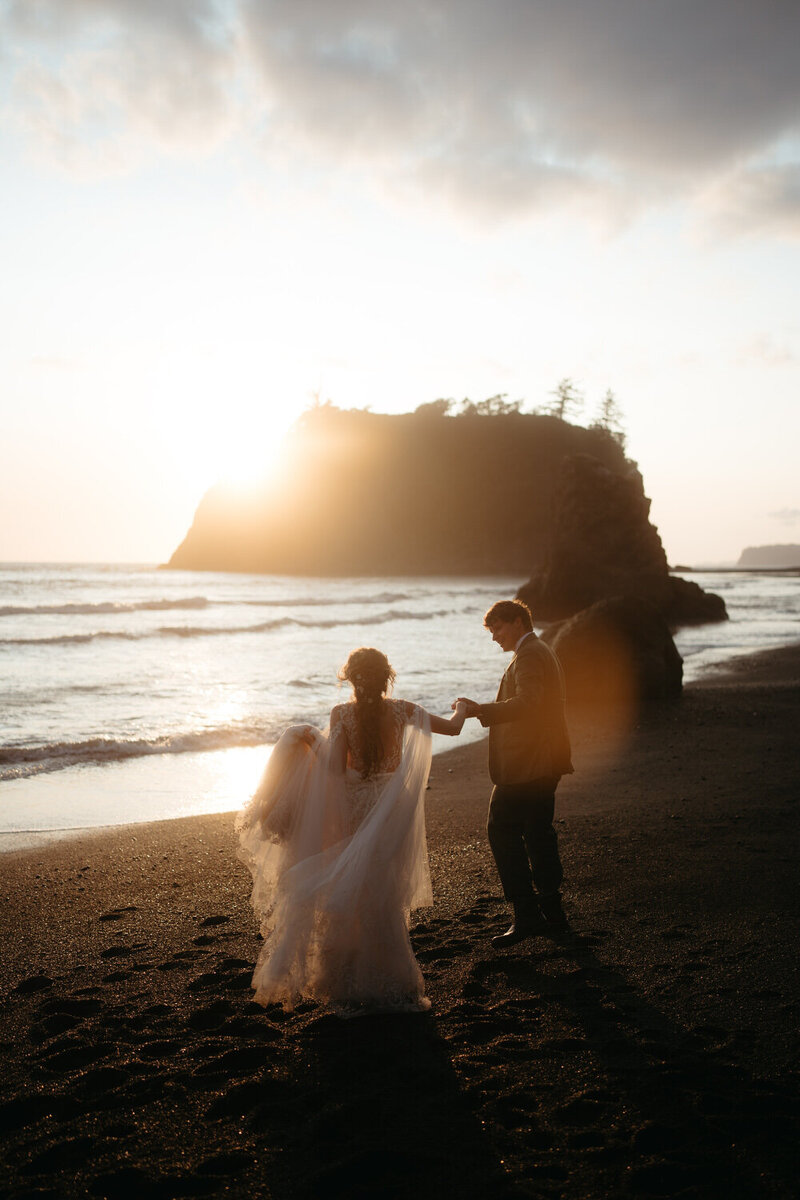 Sunset Olympic National Park Elopement, bride and groom walk hand in hand on the beach.