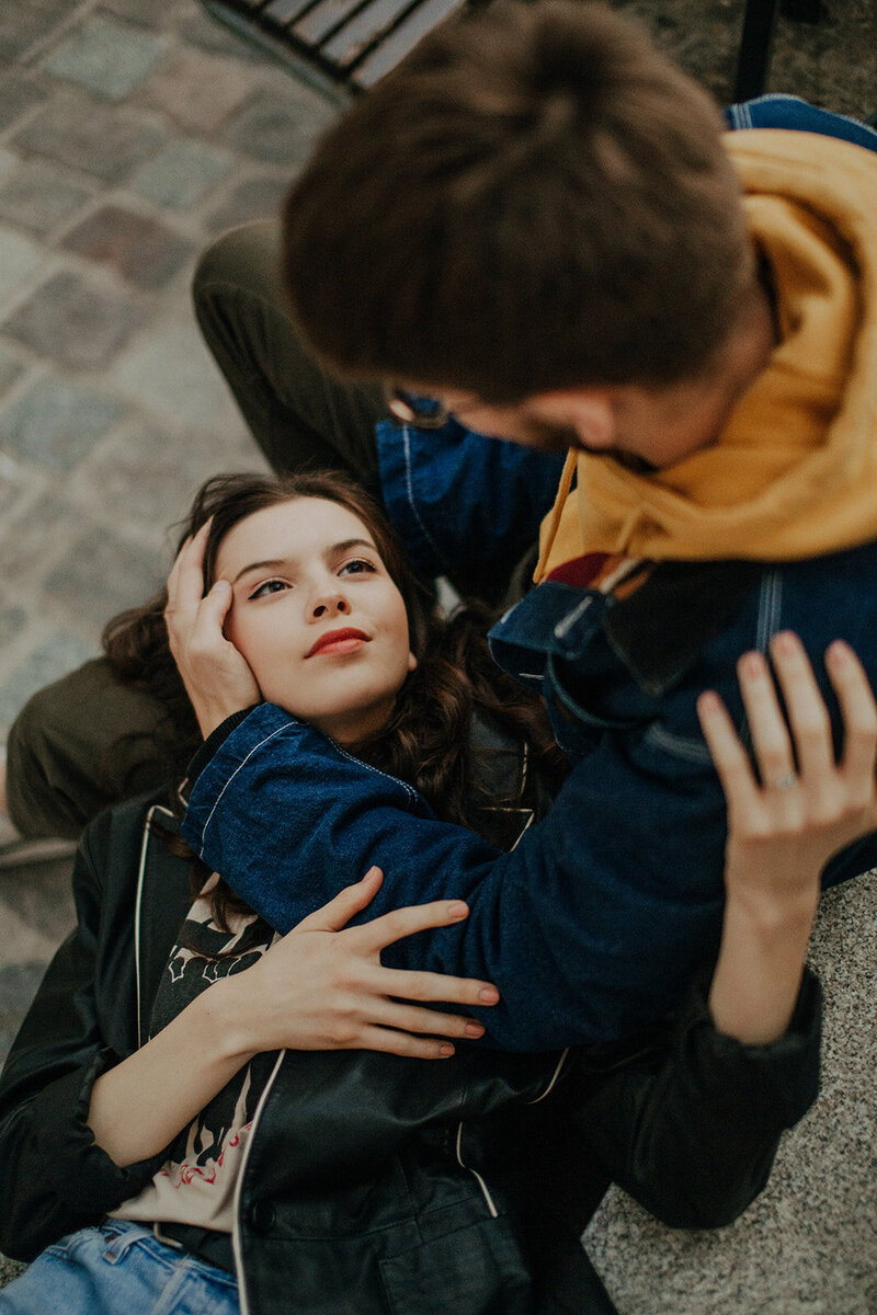 Romantic moment on the german streets captured from above, as a woman rests her head on her partner’s knees while he looks down at her lovingly.