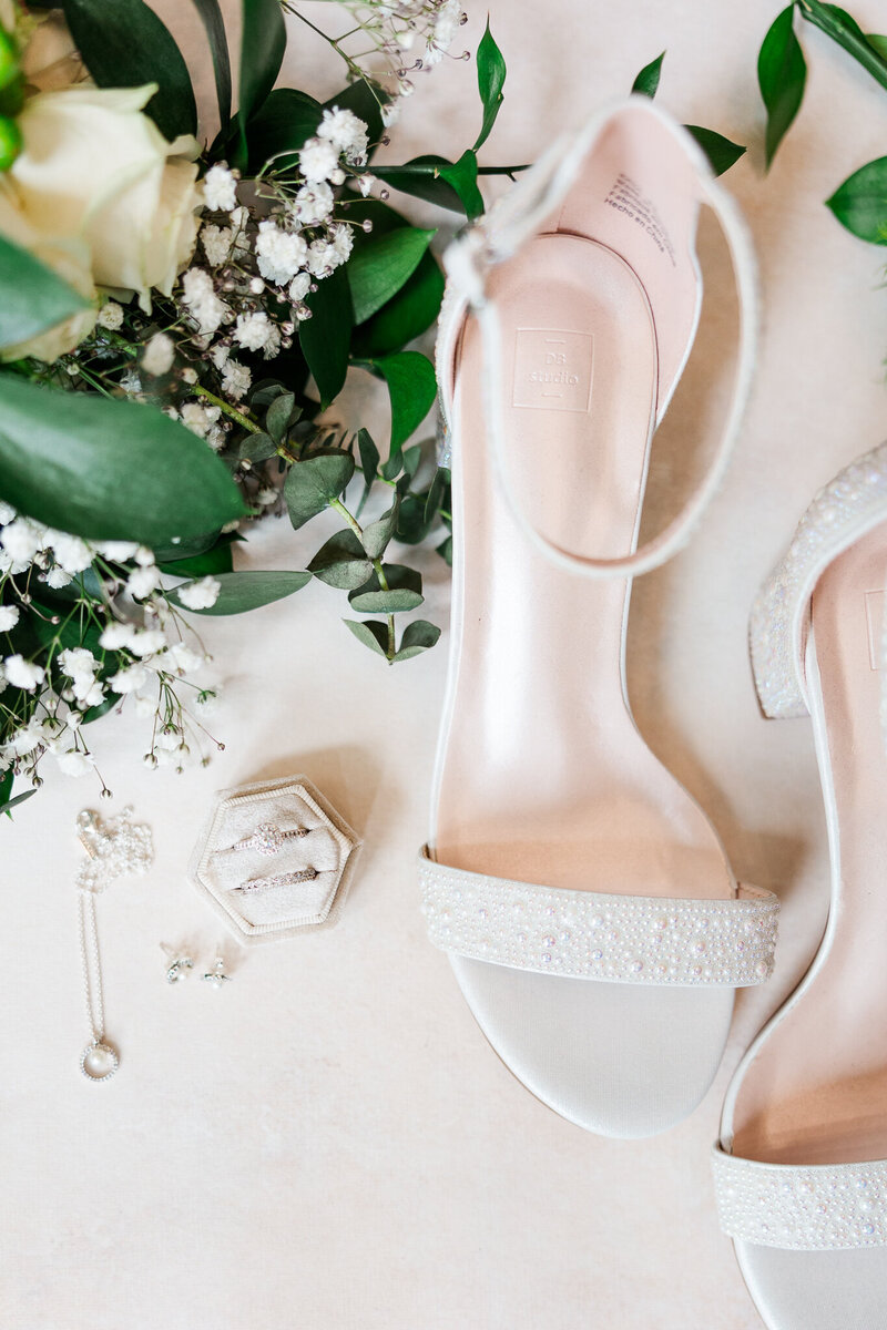 Detail shot of elegant wedding shoes and jewelry displayed in a hotel in Warren, NJ, highlighting refined preparation and sophisticated style