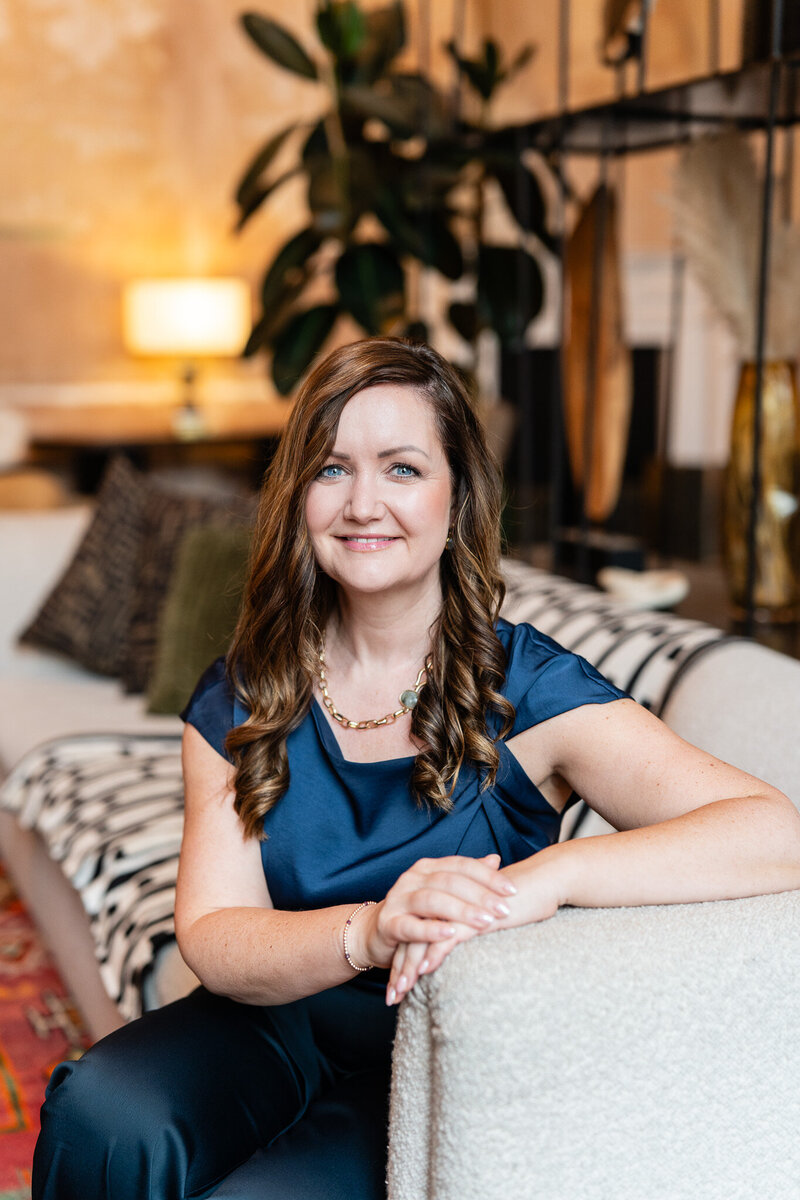 Bryony Williams in dark blue dress on a sofa