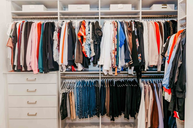 A bedroom closet featuring organized clothing on racks