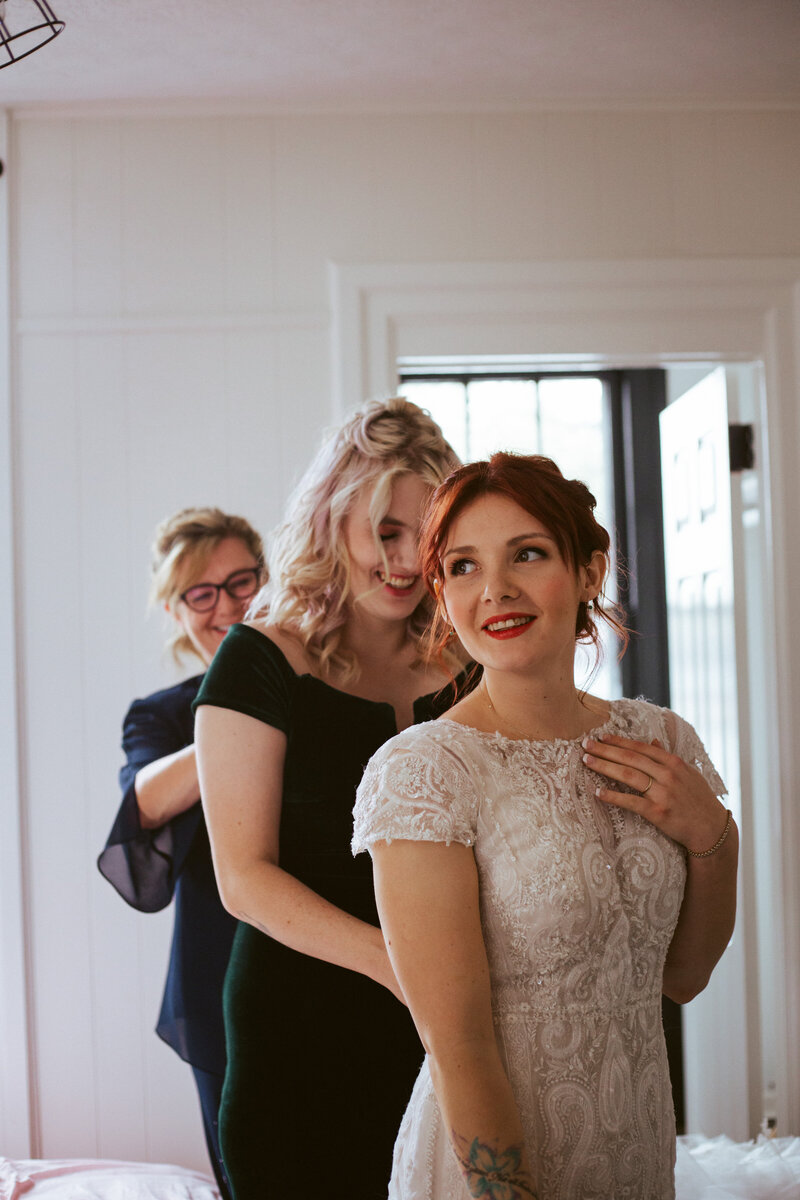 woman helping bride with wedding dress