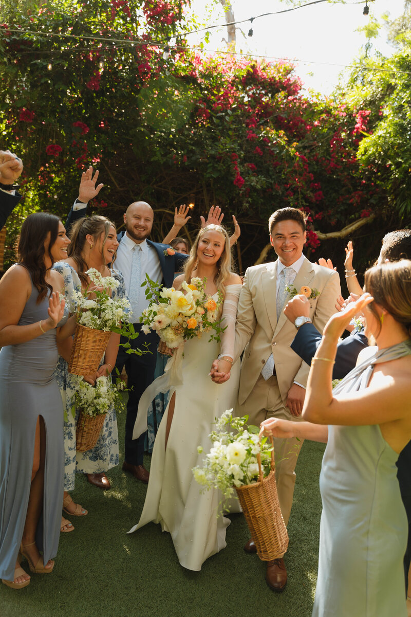 a bride and groom laughing, walking through a tunnel of their bridal party