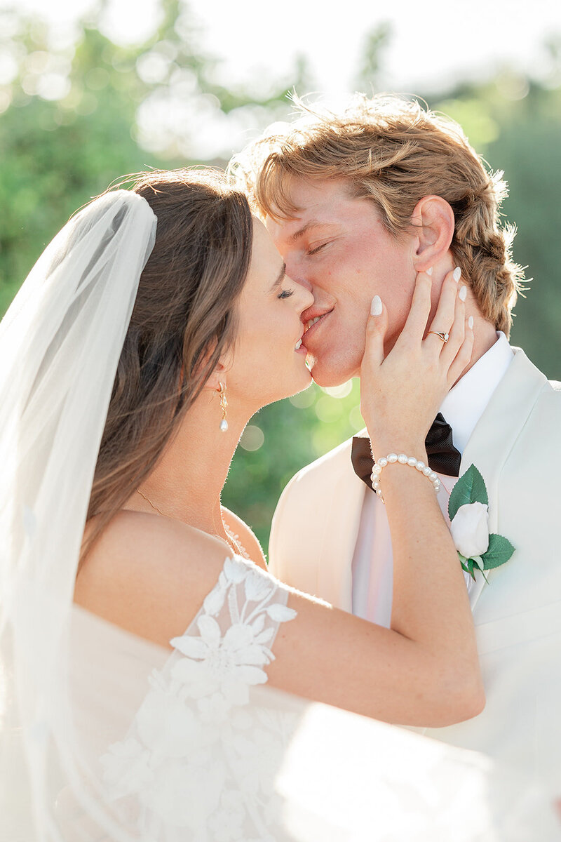 Bride and groom romantically kissing while the brides veil is flowing in the wind 