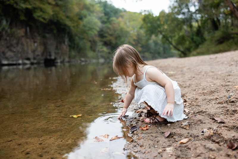 Child playing in the creek during a family portrait session in Farmington, Missouri. 
