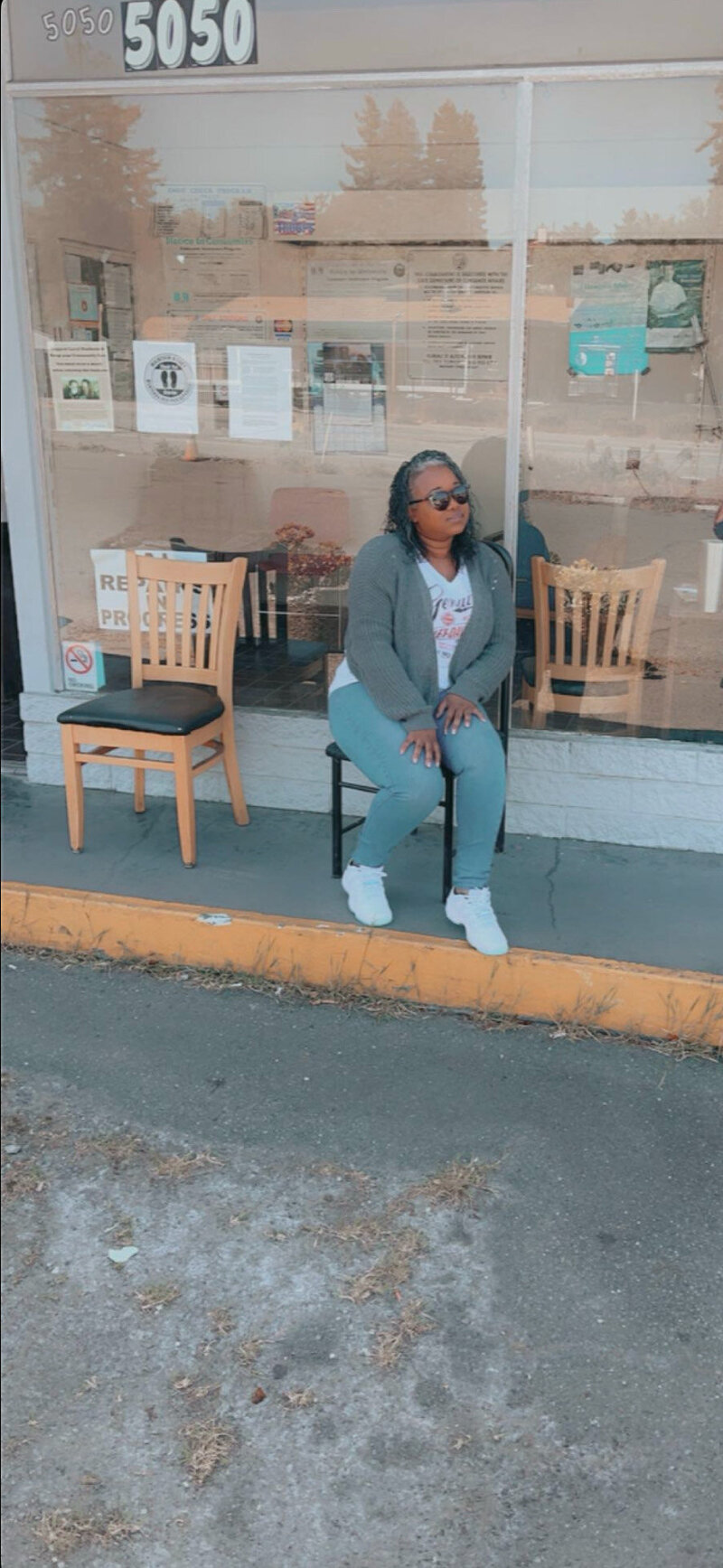 Letitia Hopkins sitting in a chair in front of a vintage building, radiating confidence, self-love, and Main Character Energy as a life, love, and relationship coach guiding women into empowered, aligned lives and relationships.