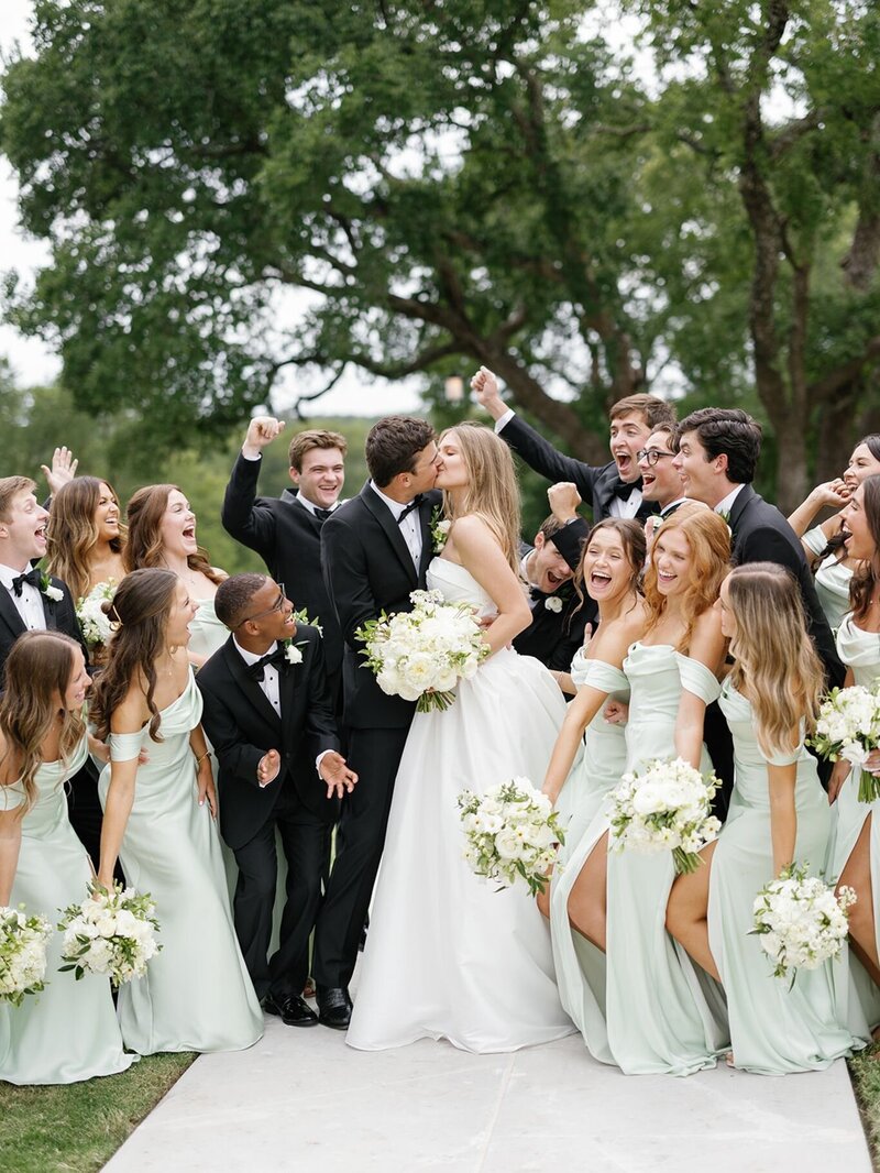 Bride and groom celebrating with bridesmaids and groomsmen dressed in light green dresses and black tuxedos.