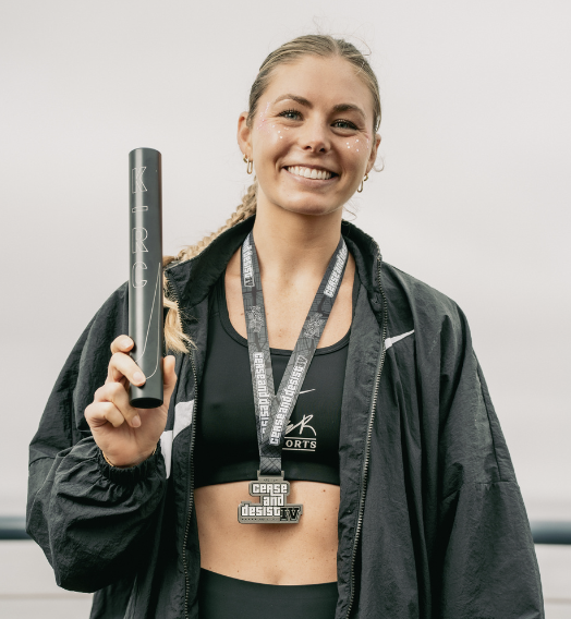 Coach Sophie Gorman smiling and holding a baton after a HER Sports Club race.